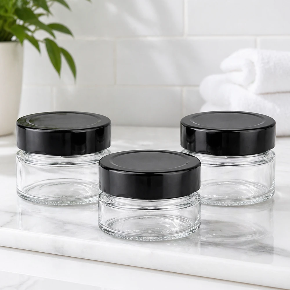 80ml rond glas met BasicSeal deksel zwart deep UNiTWIST Drie ronde potjes van 80 ml met zwarte BasicSeal deksels UNiTWIST op wit marmeren blad Sfeer badkamer leeg