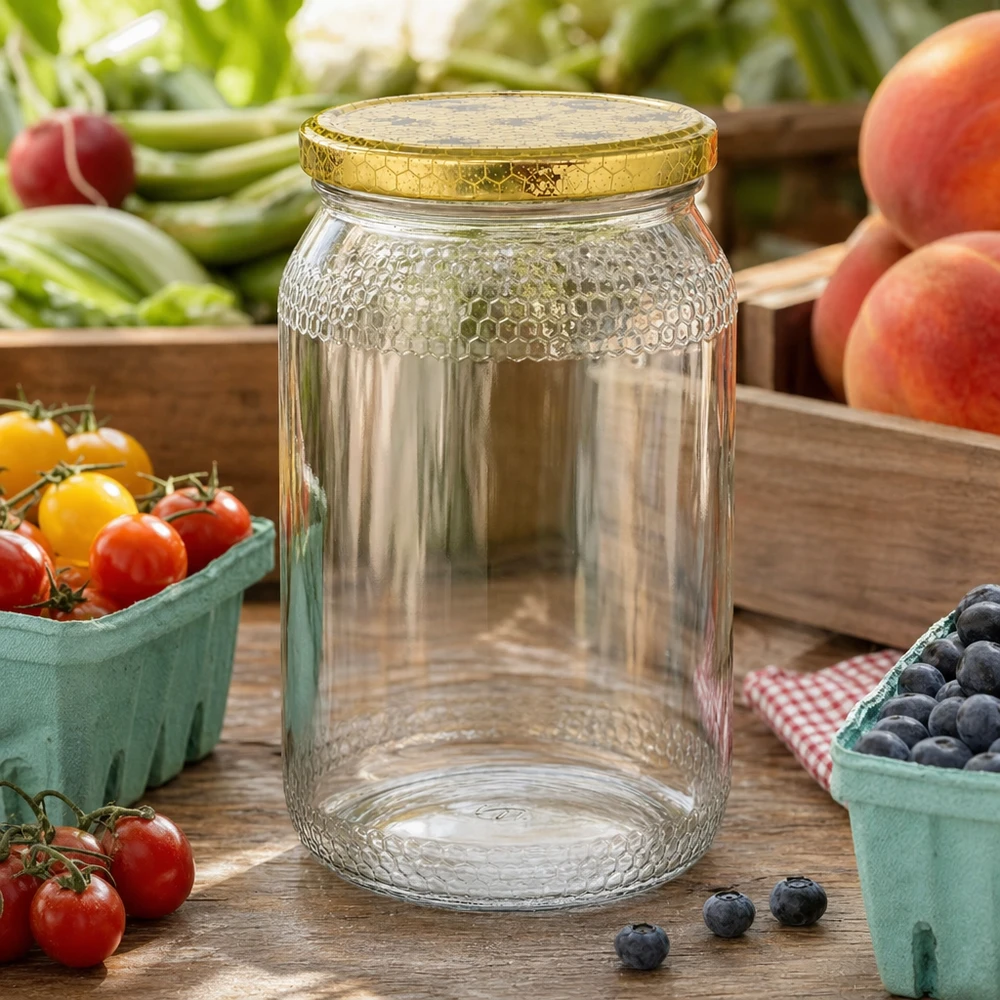 Honingpot 1260 g met honingraatmotief-deksel BasicSeal UNiTWIST 900ml honingpot leeg met gouden honingraatdeksel tussen vers fruit en groenten op houten keukentafel
