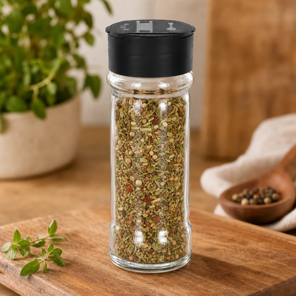 Cilindrische strooibus van helder glas, 100 ml, met een bonte kruidenmix en een zwarte dubbele deksel