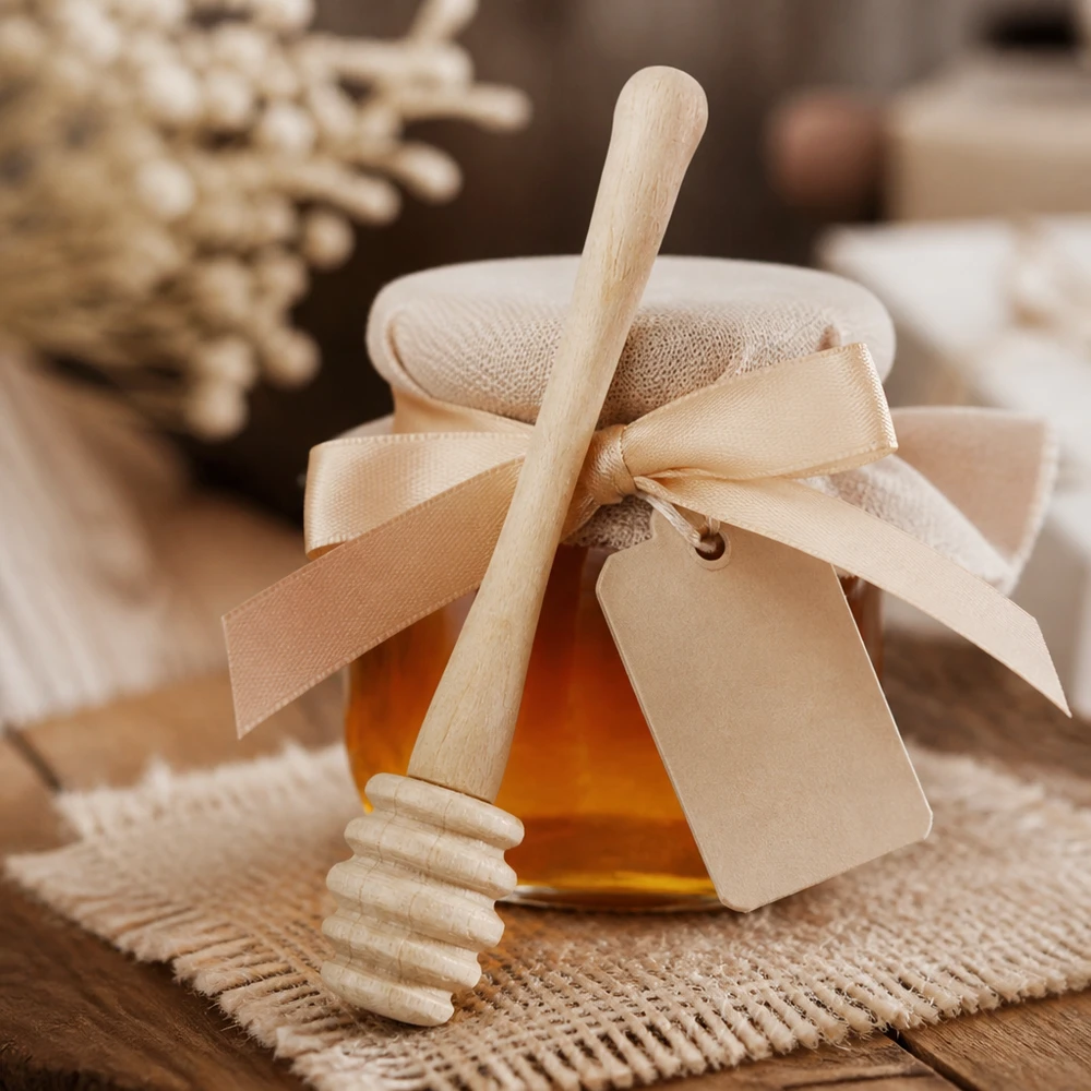 Houten honingzuiger 10,5 cm Honinglepel van esdoornhout met geschenkverpakking en lint als geschenk naast honingraten op een jute achtergrond