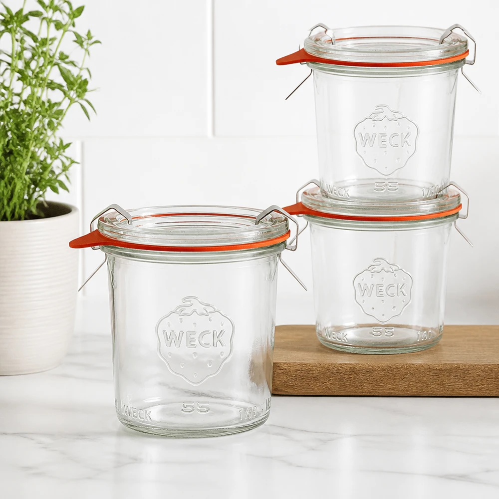 140ml stortglas compleet WECK RR60 Drie WECK 140ml RR60 bekers gestapeld op een houten plank in een moderne keuken met een groene plant op de achtergrond