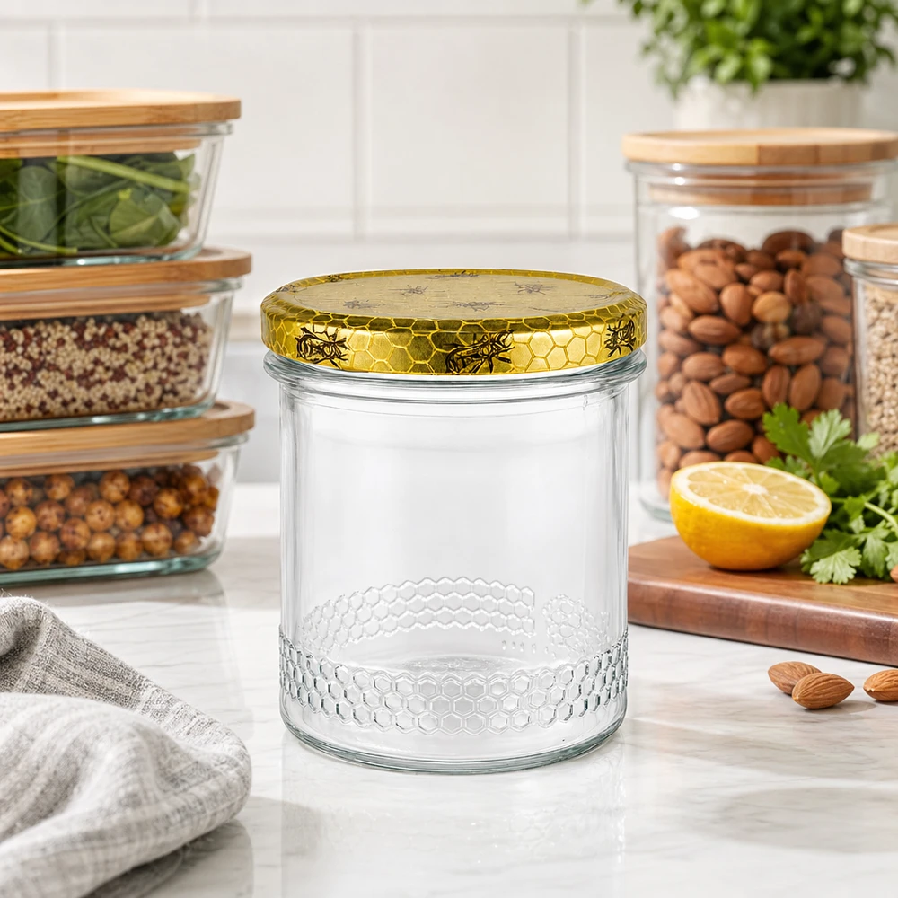 Honingpot van 400 ml met gouden honingraatdeksel op keukenblad, voorraadpotten met noten op de achtergrond